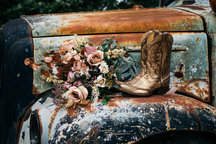 A metallic gold cowboy boot and a rustic dried faux weathered hood of an old rusted truck. Flowers by Flowers For Ever After