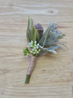 Artificial wedding boutonniere with a grey faux protea bud, pale narrow leaves, rounded eucalyptus and blush-wrapped stems. For formals, proms and ball occasions. Made in Melbourne by Flowers For Ever After, shipping Australia and Worldwide.