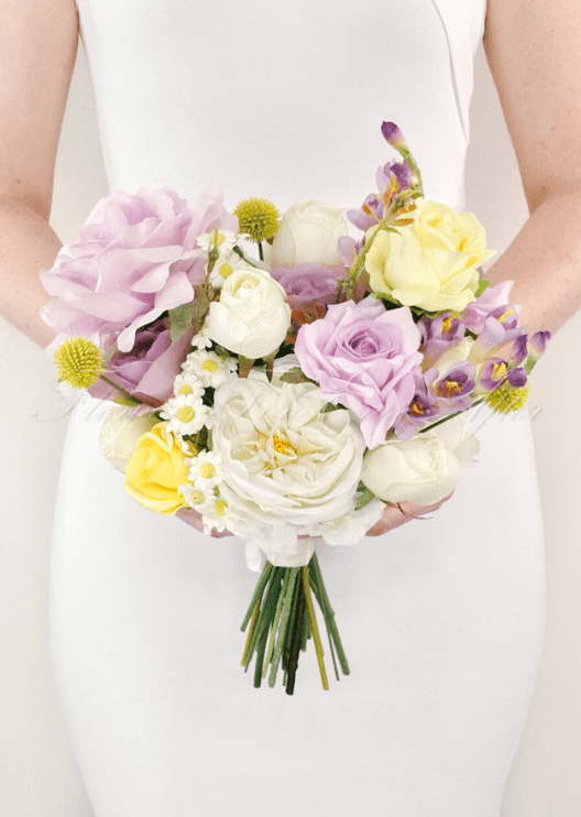Artificial wedding bridesmaid bouquet held by a woman, with lilac and yellow faux roses, white peonies, daisies and yellow button flowers. Made in Melbourne by Flowers For Ever After, shipping Australia and Worldwide.