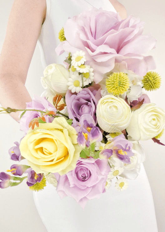 Artificial wedding bridesmaid bouquet close-up with lilac and yellow faux roses, white blooms, daisies and yellow button flowers. Made in Melbourne by Flowers For Ever After, shipping Australia and Worldwide.