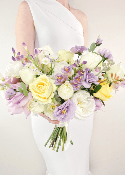 Artificial wedding bridal bouquet, handheld angled view of lilac, yellow and white faux roses with white peonies and purple flowers. Made in Melbourne by Flowers For Ever After, shipping Australia and Worldwide.