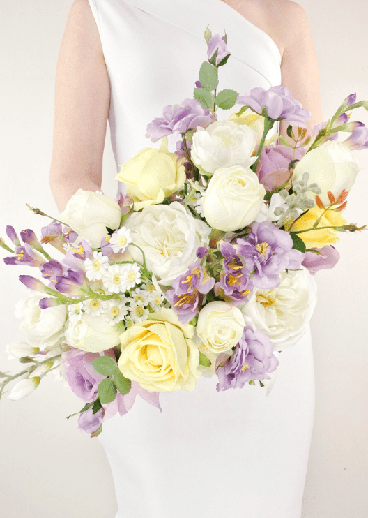 Artificial wedding bouquet, overhead view of lilac and yellow faux roses, white peonies, purple flowers and small white blooms. Made in Melbourne by Flowers For Ever After, shipping Australia and Worldwide.