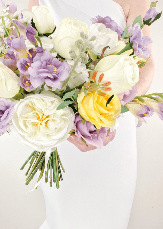 Artificial wedding bouquet detail with yellow and white faux roses, white peonies, purple flowers and green stems. Made in Melbourne by Flowers For Ever After, shipping Australia and Worldwide.