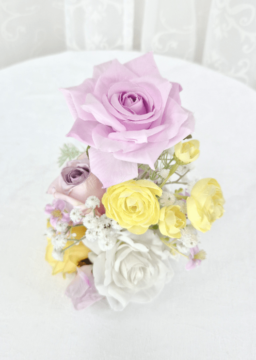 Artificial wedding small table arrangement, overhead view of lilac, yellow and white faux roses with fine white sprigs. Made in Melbourne by Flowers For Ever After, shipping Australia and Worldwide.