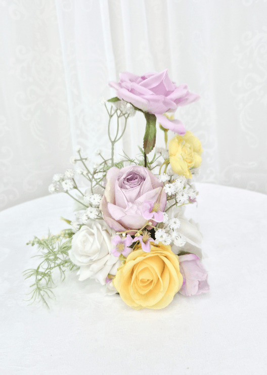 Artificial wedding small table arrangement with a raised lilac faux rose, yellow and white roses and fine white sprigs. Made in Melbourne by Flowers For Ever After, shipping Australia and Worldwide.