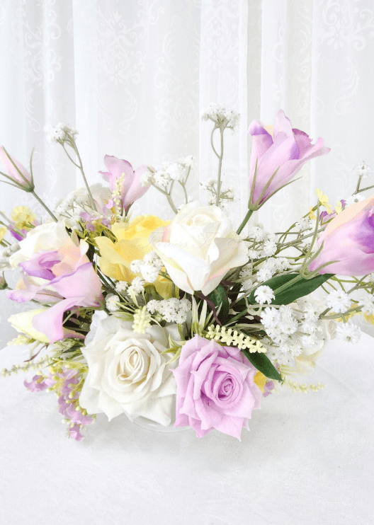 Artificial wedding table centrepiece, angled view of white and lilac faux roses, yellow blooms and fine branching white sprigs. Made in Melbourne by Flowers For Ever After, shipping Australia and Worldwide.