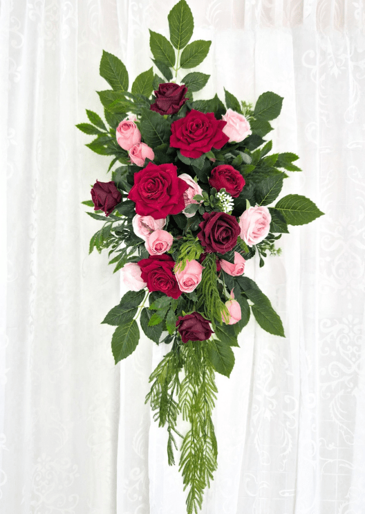Artificial wedding hanging arbor arrangement with red, burgundy and pink faux roses, broad green leaves and long fern-like foliage. Made in Melbourne by Flowers For Ever After, shipping Australia and Worldwide.