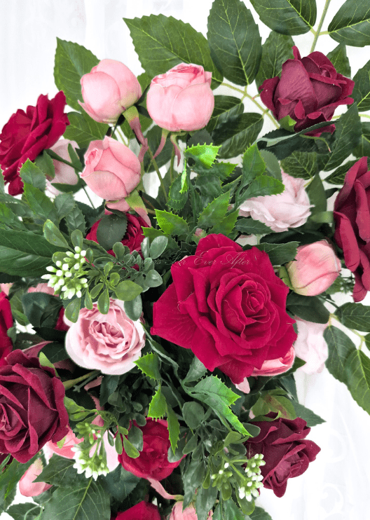 Artificial wedding arbor flower detail showing pink faux rosebuds, red and burgundy roses, white sprigs and broad green leaves. Made in Melbourne by Flowers For Ever After, shipping Australia and Worldwide.