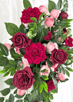 Artificial wedding arbor arrangement close-up with red and burgundy faux roses, pink rosebuds, small white sprigs and layered green foliage. Made in Melbourne by Flowers For Ever After, shipping Australia and Worldwide.