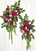 Artificial wedding arbor floral set with two hanging arrangements of red, burgundy and pink faux roses, broad leaves and trailing greenery. Made in Melbourne by Flowers For Ever After, shipping Australia and Worldwide.