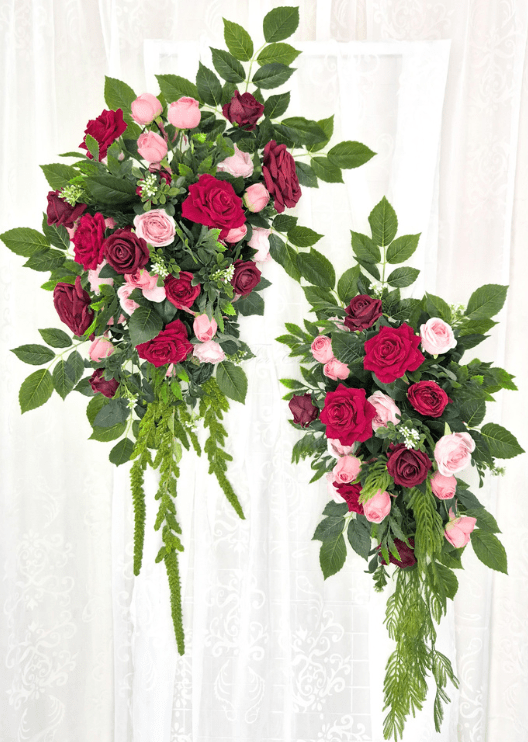 Artificial wedding arbor floral set with two hanging arrangements of red, burgundy and pink faux roses, broad leaves and trailing greenery. Made in Melbourne by Flowers For Ever After, shipping Australia and Worldwide.