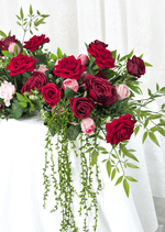 Artificial wedding table arrangement, angled view of red, burgundy and pink faux roses with long cascading green strands. Made in Melbourne by Flowers For Ever After, shipping Australia and Worldwide.
