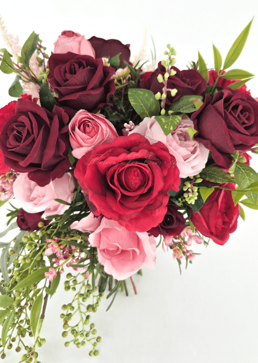 Artificial wedding bridal bouquet close-up with red, burgundy and pink faux roses, tiny pink blossoms and trailing green berry sprigs. Made in Melbourne by Flowers For Ever After, shipping Australia and Worldwide.