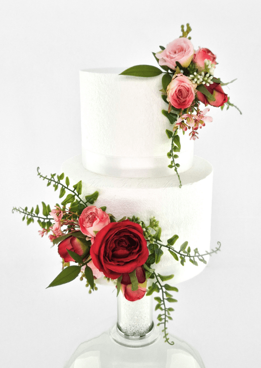 Artificial wedding cake decoration with red and pink faux roses, small pink flowers and green sprigs in upper and lower clusters. For birthday, event and celebration cakes. Made in Melbourne by Flowers For Ever After, shipping Australia and Worldwide.