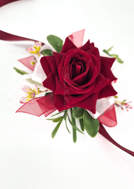 Artificial wedding wrist corsage with a burgundy faux rose, tiny pink blossoms, green leaves and burgundy and white ribbons. For formals, proms and ball occasions. Made in Melbourne by Flowers For Ever After, shipping Australia and Worldwide.