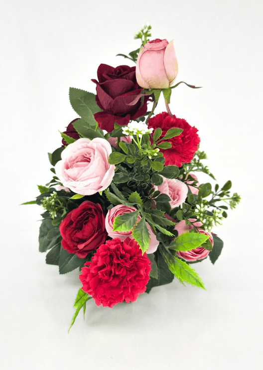 Artificial wedding table arrangement, angled view of pink and burgundy faux roses, red carnations, white flower sprigs and fern-like foliage. Made in Melbourne by Flowers For Ever After, shipping Australia and Worldwide.