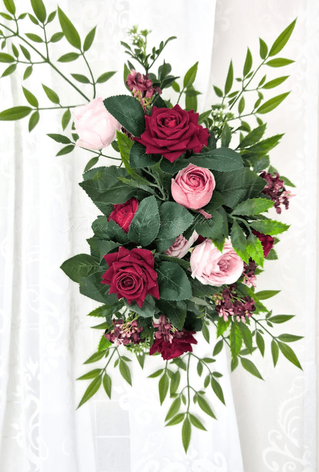 Artificial wedding floral tieback with burgundy and pink faux roses, small mauve blossoms and spreading green foliage. Made in Melbourne by Flowers For Ever After, shipping Australia and Worldwide.