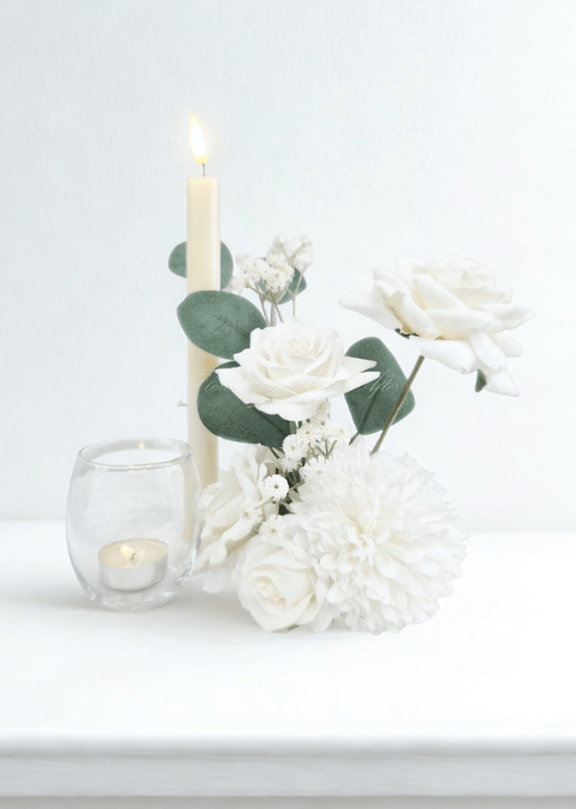 Artificial wedding small table arrangement with white faux roses, white pompom bloom and rounded eucalyptus leaves beside candles. Made in Melbourne by Flowers For Ever After, shipping Australia and Worldwide.