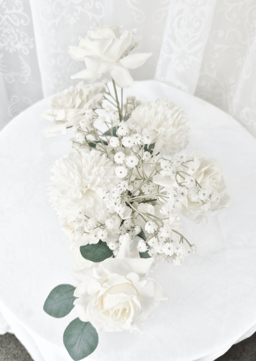 Artificial wedding table arrangement, overhead view of white faux roses, white pompom blooms, tiny flowers and eucalyptus. Made in Melbourne by Flowers For Ever After, shipping Australia and Worldwide.