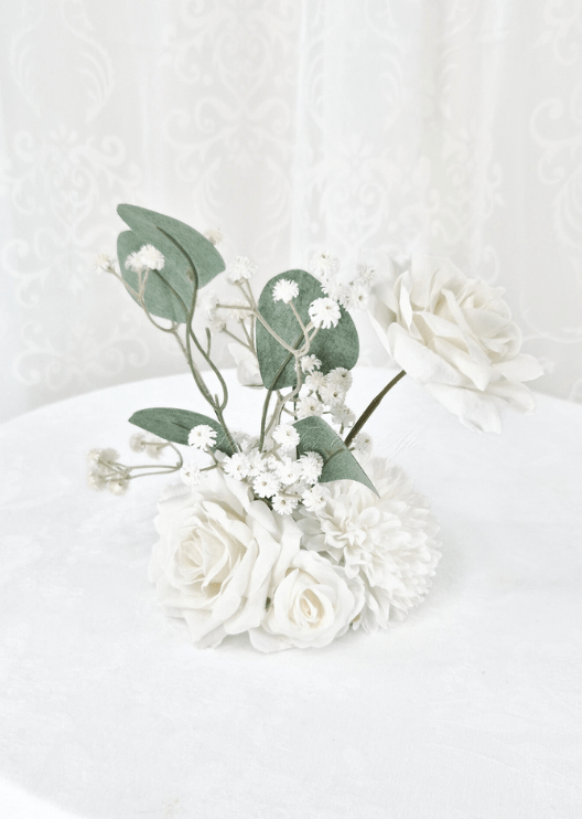 Artificial wedding small table arrangement, angled view of white faux roses, white pompom bloom, tiny flowers and eucalyptus. Made in Melbourne by Flowers For Ever After, shipping Australia and Worldwide.