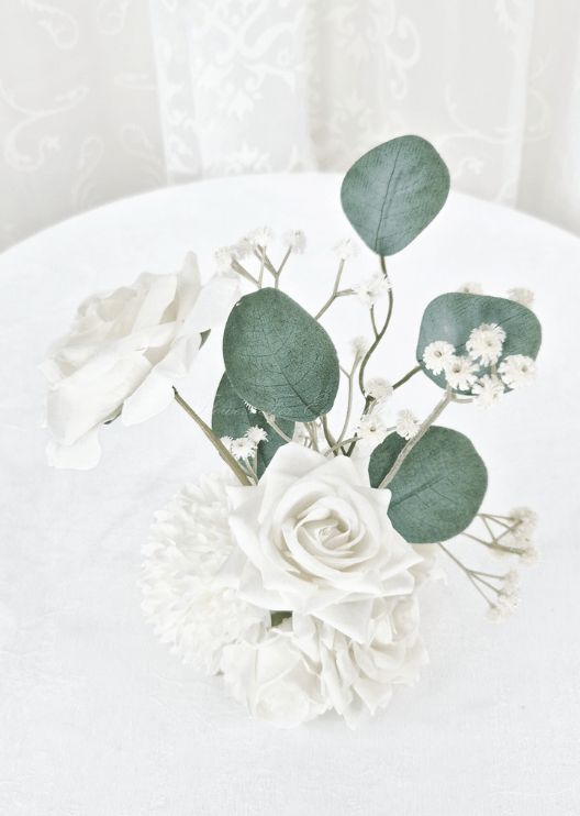 Artificial wedding small table arrangement, overhead view of white faux roses, tiny white flowers and rounded eucalyptus leaves. Made in Melbourne by Flowers For Ever After, shipping Australia and Worldwide.