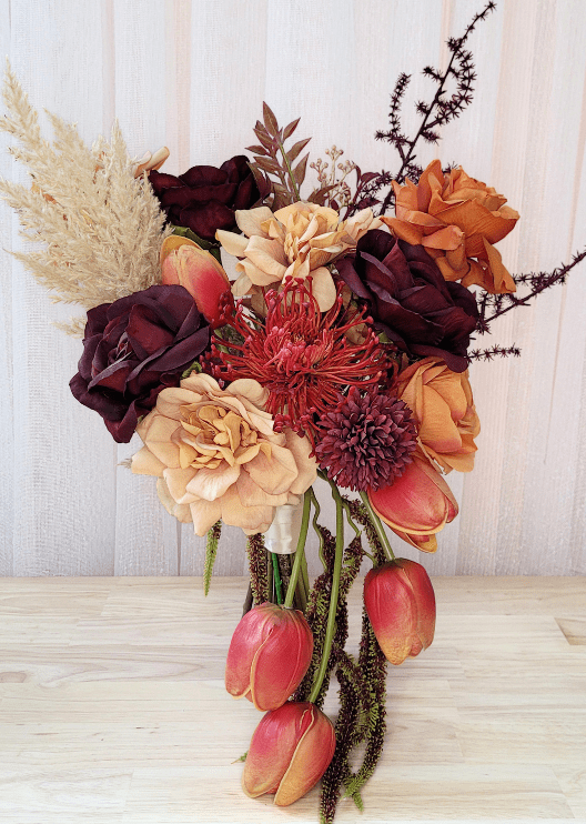Artificial wedding bridal bouquet with orange, burgundy and beige faux roses, red spiky bloom, burgundy chrysanthemum, trailing tulips and pale plumes. Made in Melbourne by Flowers For Ever After, shipping Australia and Worldwide.