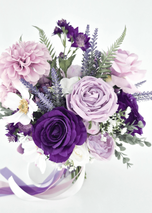 Artificial wedding bridal bouquet, angled view of purple and lilac faux roses, pink dahlias, white gold-centred flowers and trailing ribbons. Made in Melbourne by Flowers For Ever After, shipping Australia and Worldwide.