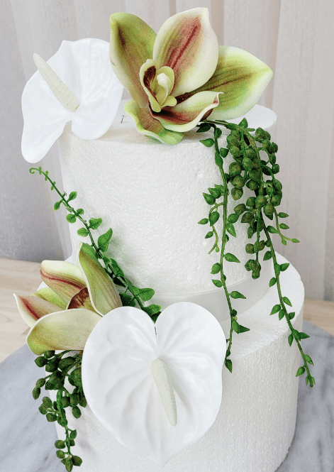 Artificial wedding cake flower close-up with white faux anthuriums, green-and-burgundy orchids and long green strands. For birthday, event and celebration cakes. Made in Melbourne by Flowers For Ever After, shipping Australia and Worldwide.