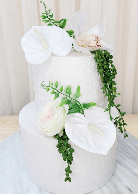 Artificial wedding cake decoration with white faux anthuriums, pale speckled orchid, ivory-blush rose and trailing greenery. For birthday, event and celebration cakes. Made in Melbourne by Flowers For Ever After, shipping Australia and Worldwide.