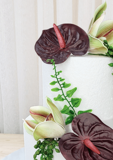 Artificial wedding cake flower close-up with burgundy faux anthuriums, green-and-burgundy orchids and trailing green leaves. For birthday, event and celebration cakes. Made in Melbourne by Flowers For Ever After, shipping Australia and Worldwide.