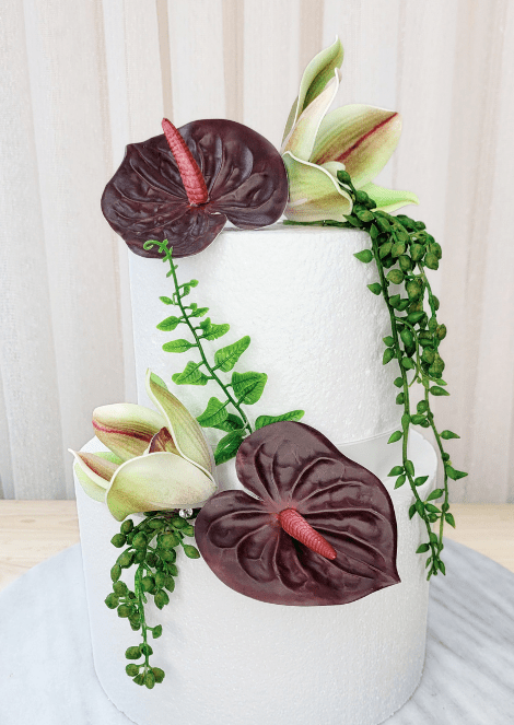 Artificial wedding cake decoration, full view of burgundy faux anthuriums, green-and-burgundy orchids and green leaves. For birthday, event and celebration cakes. Made in Melbourne by Flowers For Ever After, shipping Australia and Worldwide.