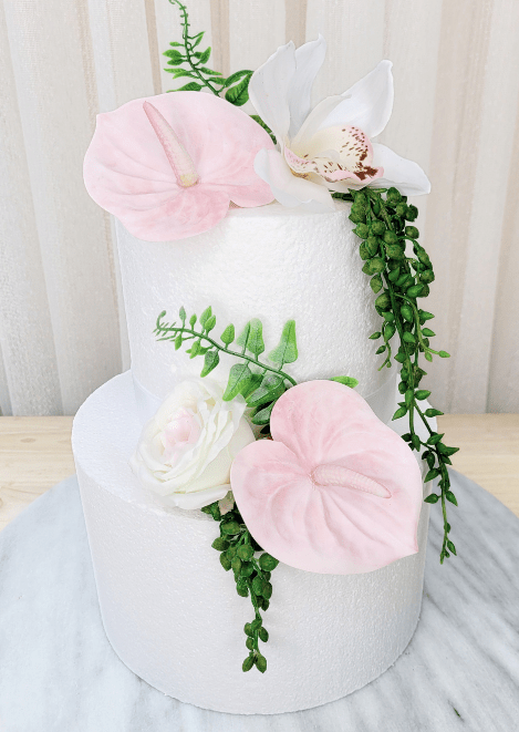 Artificial wedding cake decoration, front view of pale pink faux anthuriums, white speckled orchid, ivory-blush rose and green strands. For birthday, event and celebration cakes. Made in Melbourne by Flowers For Ever After, shipping Australia and Worldwide.