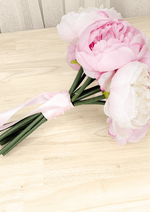 Artificial wedding small bouquet laid sideways, showing pink and ivory faux peonies, pink ribbon and gathered green stems. Made in Melbourne by Flowers For Ever After, shipping Australia and Worldwide.