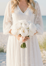Artificial wedding bouquet held by a person in a white lace-sleeved dress, with white faux peonies and gathered green stems. Made in Melbourne by Flowers For Ever After, shipping Australia and Worldwide.