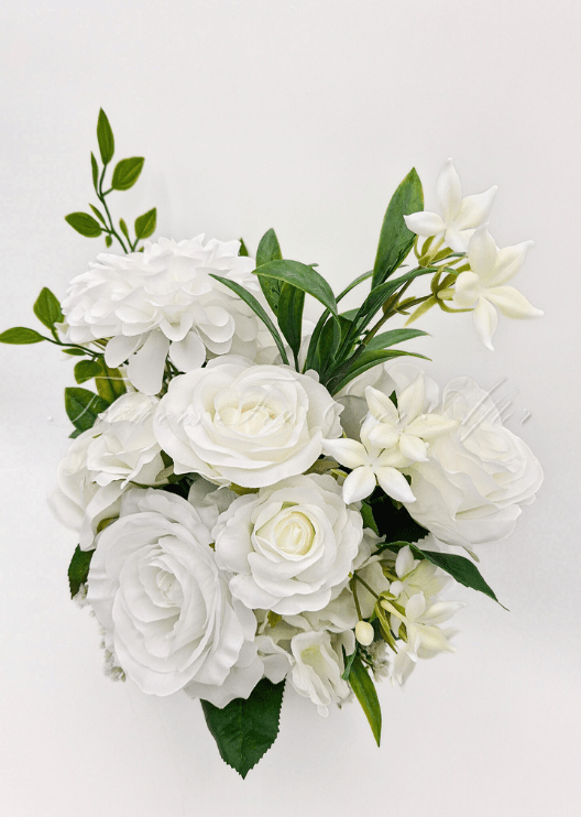 Artificial wedding bridesmaid bouquet, top view of white faux roses, round white blooms and small white flowers among green leaves. Made in Melbourne by Flowers For Ever After, shipping Australia and Worldwide.