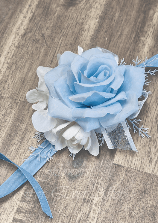 Artificial wedding wrist corsage with light blue faux roses, small white flowers, green leaves and ivory ribbon ties. For formals, proms and ball occasions. Made in Melbourne by Flowers For Ever After, shipping Australia and Worldwide.