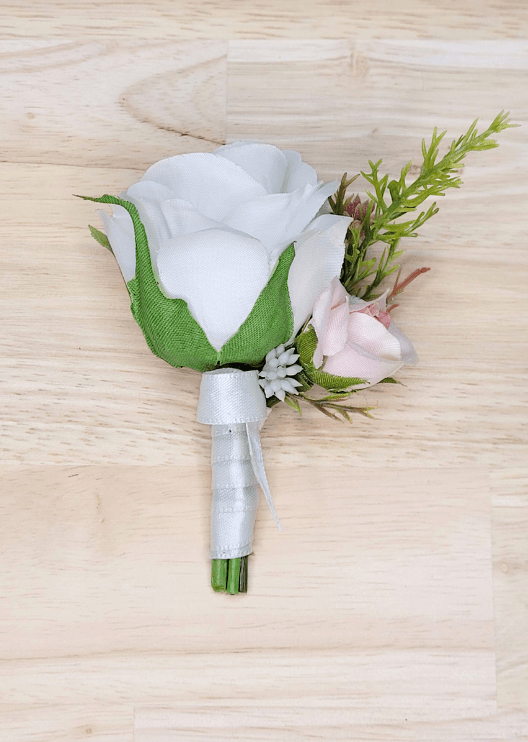 Artificial wedding boutonniere with a white faux rose, pale blush rosebud, tiny white flowers and a green sprig, with ivory-wrapped stems. For formals, proms and ball occasions. Made in Melbourne by Flowers For Ever After, shipping Australia and Worldwide.