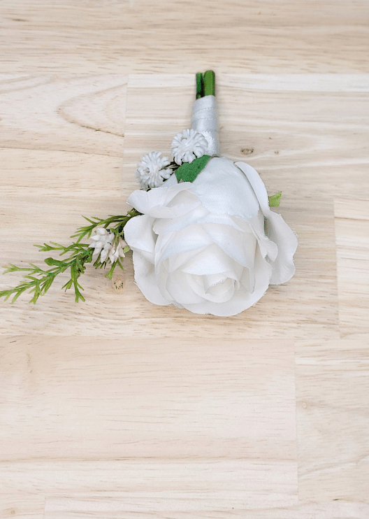 Artificial wedding boutonniere, top view of a white faux rose with tiny white flowers and a green sprig. For formals, proms and ball occasions. Made in Melbourne by Flowers For Ever After, shipping Australia and Worldwide.
