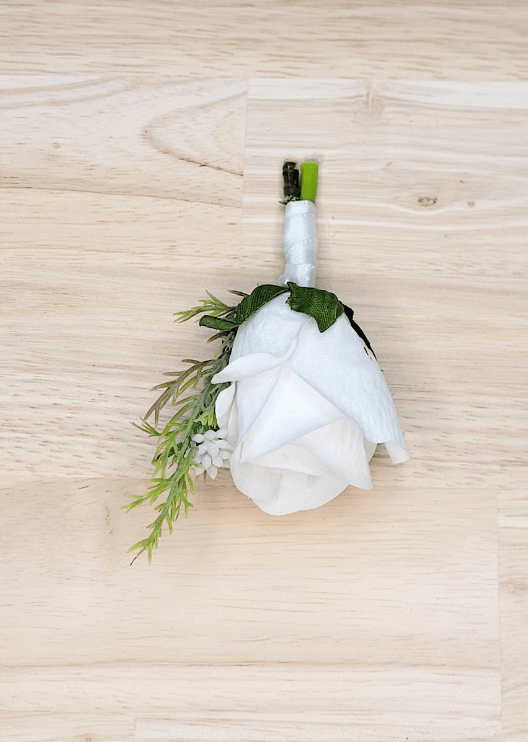 Artificial wedding page boy boutonniere, top view of a white faux rose and delicate green sprig. For formals, proms and ball occasions. Made in Melbourne by Flowers For Ever After, shipping Australia and Worldwide.