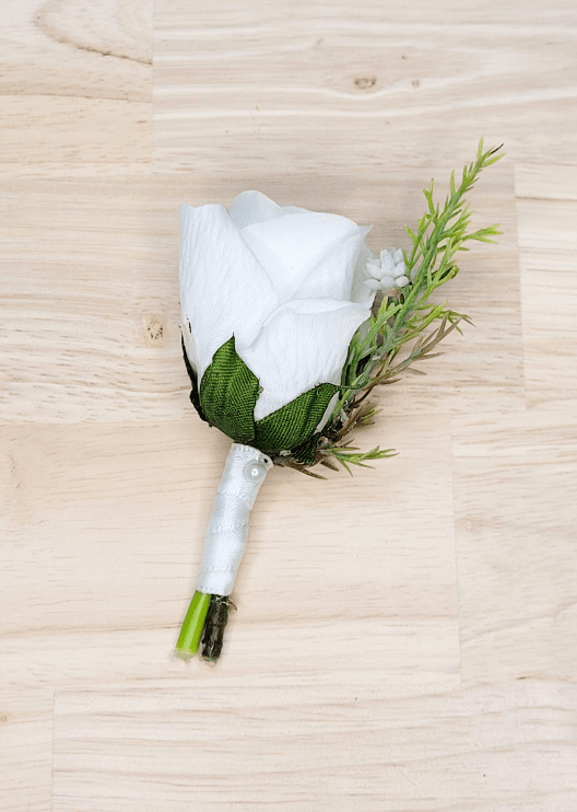 Artificial wedding page boy boutonniere with a white faux rose, tiny white flowers and a fine green sprig, with ivory-wrapped stems. For formals, proms and ball occasions. Made in Melbourne by Flowers For Ever After, shipping Australia and Worldwide.