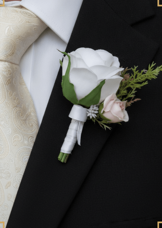 Artificial wedding boutonniere worn on a lapel, with a white faux rose, pale blush rosebud and green foliage. For formals, proms and ball occasions. Made in Melbourne by Flowers For Ever After, shipping Australia and Worldwide.