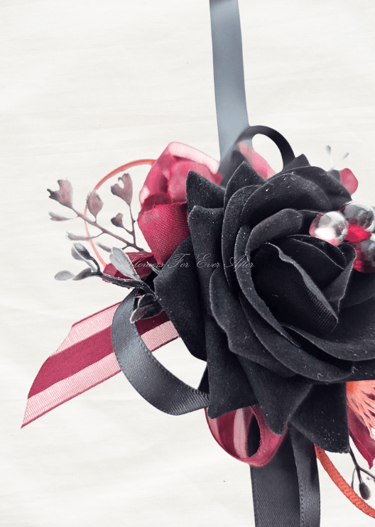 Artificial wedding corsage ribbon detail showing black and burgundy loops beside a black faux rose and dark sprigs. For formals, proms and ball occasions. Made in Melbourne by Flowers For Ever After, shipping Australia and Worldwide.