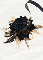 Artificial wedding wrist corsage, angled view of a black faux rose, amber jewels, golden sprigs and black and gold ribbon loops. For formals, proms and ball occasions. Made in Melbourne by Flowers For Ever After, shipping Australia and Worldwide.
