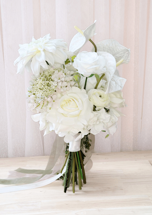 Artificial wedding bridal bouquet, reverse view of white faux dahlias, roses, ranunculus and anthuriums with gathered stems and trailing ribbons. Made in Melbourne by Flowers For Ever After, shipping Australia and Worldwide.