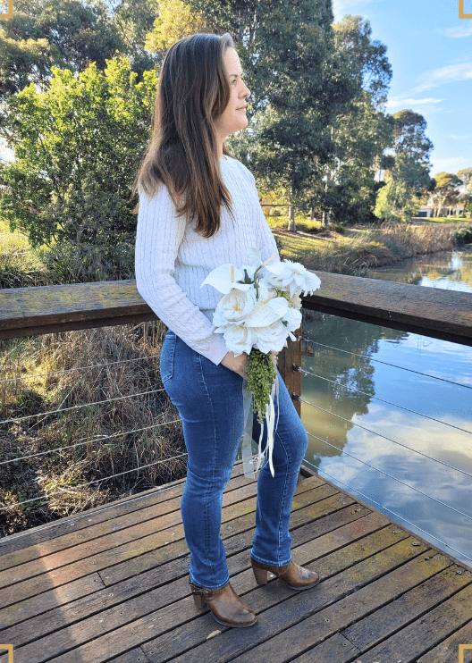 Artificial wedding bouquet held by a person in profile, with white faux anthuriums and blooms, trailing green berries and long ribbons. Made in Melbourne by Flowers For Ever After, shipping Australia and Worldwide.