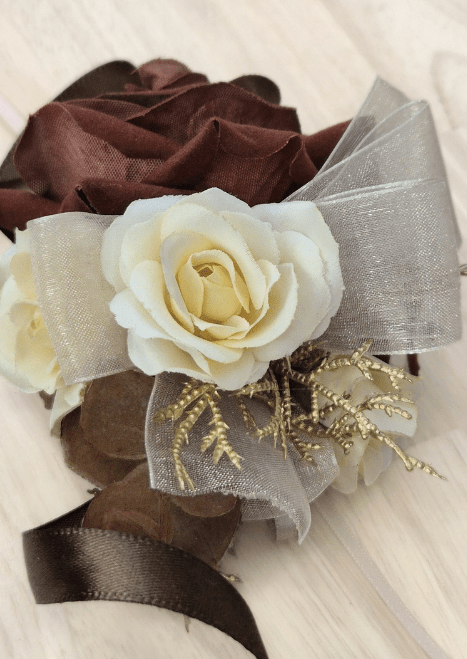 Artificial wedding corsage close-up with ivory and brown faux roses, golden sprigs and ivory organza ribbon loops. For formals, proms and ball occasions. Made in Melbourne by Flowers For Ever After, shipping Australia and Worldwide.