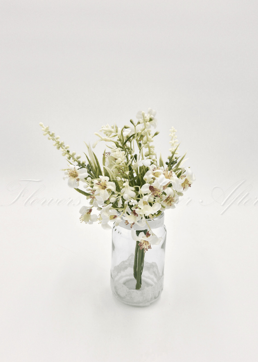 Artificial wedding table arrangement with small cream faux flowers and narrow green leaves in a clear glass jar. Made in Melbourne by Flowers For Ever After, shipping Australia and Worldwide.