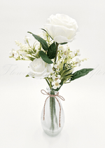 Artificial wedding table arrangement with white faux roses, tiny cream flowers and green leaves in a ribbed glass bottle tied with twine. Made in Melbourne by Flowers For Ever After, shipping Australia and Worldwide.