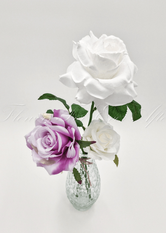 Artificial wedding table arrangement, angled view of faux roses and green leaves in a glass bottle. Made in Melbourne by Flowers For Ever After, shipping Australia and Worldwide.