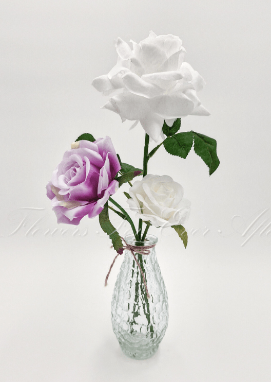 Artificial wedding table arrangement with faux roses and green foliage in a clear glass bottle. Made in Melbourne by Flowers For Ever After, shipping Australia and Worldwide.